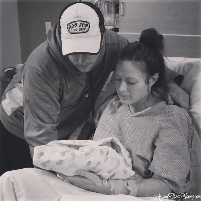 Birth Story by popular Utah motherhood blog, Among the Young: black and white image of a mom and dad holding their newborn son. 