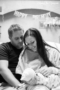 Stork OTC | Birth Story by popular Utah motherhood blog, Among the Young: black and white image of a mom and dad sitting together in a hospital bed while they hold their newborn daughter. 