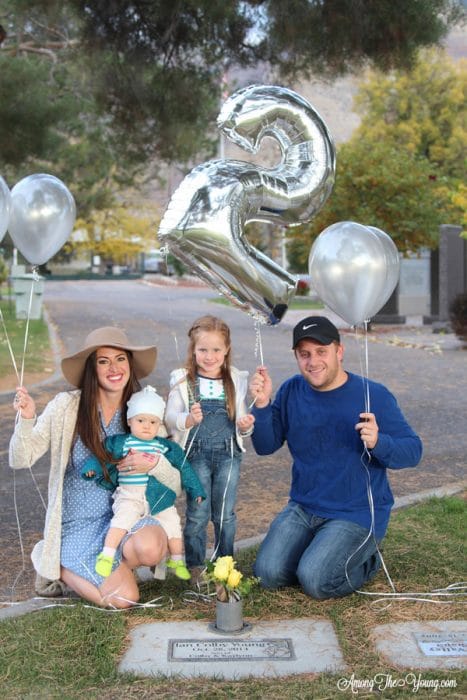 sibling loss featured by top Utah lifestyle blog, Among the Young: image of second birthday&quot | Sibling Loss: 7 Essential Tips to Help your Child Grieve by popular Utah lifestyle blog, Among the Young: image of a family kneeling by a headstone and holding silver balloons.