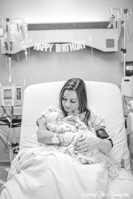 Baby girl birth story by top Utah lifestyle blog, Among the Young: image of mom holding the baby | Birth Story by popular Utah motherhood blog, Among the Young: black and white image of a mom sitting in a hospital bed and holding her newborn daughter in her arms. 
