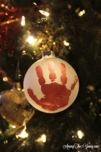 The cutest DIY handprint ornament featured by top Utah craft blog, Among the Young: image of red handprint ornament in tree