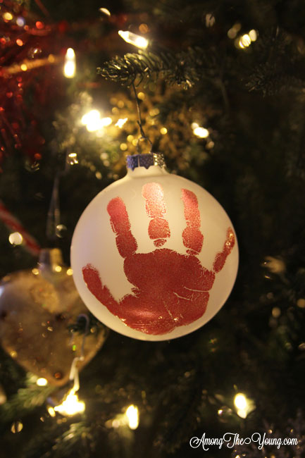 The cutest DIY handprint ornament featured by top Utah craft blog, Among the Young: image of red handprint ornament in tree | How to make the cutest DIY handprint ornament by popular Utah life and style blog, Among the Young: image of a DIY handprint ornament.