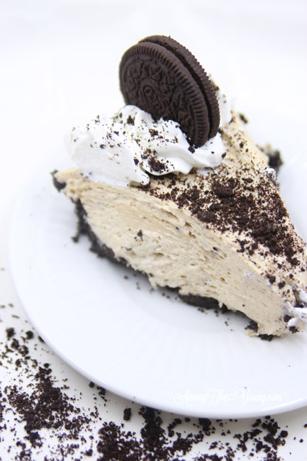 The Best Peanut Butter Pie recipe by top Utah Foodie blog, Among the Young: image of peanut butter pie slice with Oreo cookie on top | Easy Peanut Butter Pie Recipe by popular Utah food blog, Among the Young: a slice of peanut butter pie on white plate that's surrounded by crushed Oreos. 