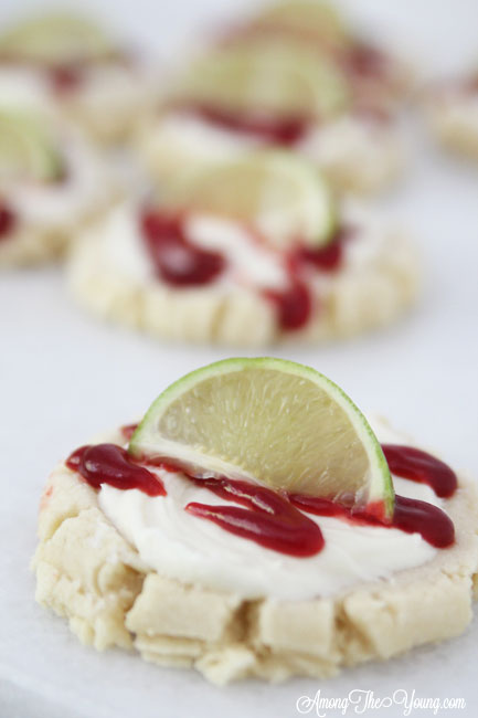 The most amazing raspberry lime sugar cookies featured by top Utah Foodie blog Among the Young: image of one cookie close up with a lime | Key Lime Raspberry Sugar Cookies by popular Utah food blog, Among the Young: image of key lime raspberry sugar cookies.
