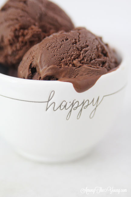 The Best Chocolate ice cream featured by top Utah Foodie blog Among the Young: image of HAPPY bowl | Chocolate Ice Cream Recipe by popular Utah food blog, Among the Young: image of chocolate ice cream in some white stacked ceramic bowls and a metal ice cream scoop. 