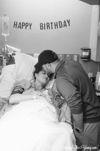 in hospital bed, husband kisses wife